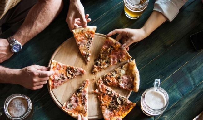 a group of people eating pizza